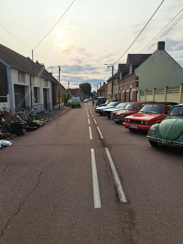 Rue du village bordée de véhicules anciens